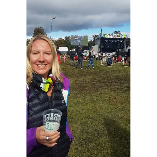 Woman wearing her world champion rainbow Ruffnek neck gaiter as a supporters scarf whilst watching the UCI cycle race on the big screen in Harrogate 2019. World Cycling Champion Multi Scarf – a versatile, breathable accessory for UK cyclists. Perfect for rides in all weather. #CyclingGear #UKCyclingStyle #CyclingGear, #BikeAccessories, #MultiScarf