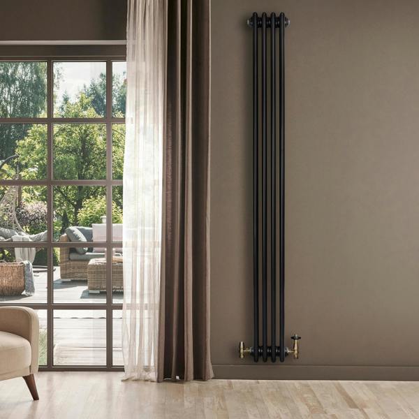 Sleek black traditional 4 column radiator with brass valves, mounted on a warm-toned wall, enhancing a modern living space