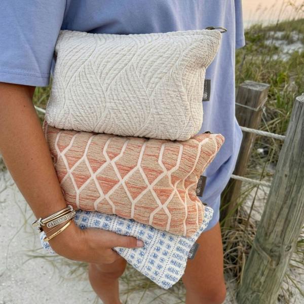 Indigo jacquard toiletry bag folded with zip-top opening held in hands