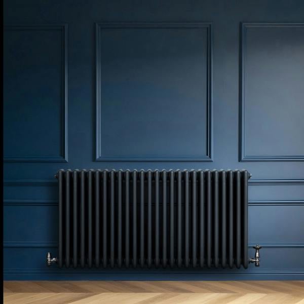 Traditional anthracite grey 4 column radiator with sleek vertical lines, mounted against a deep blue wall, enhancing modern decor