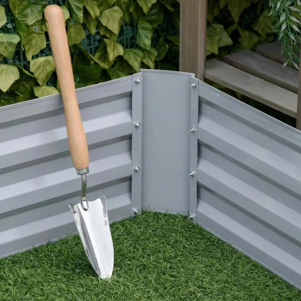 Grey elevated planter bed corner with shovel tool resting against the frame