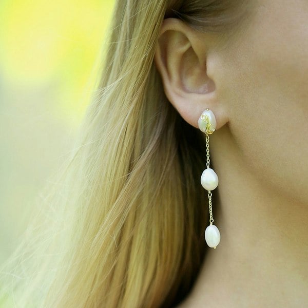 An ear with gold vermeil triple pearl drop earrings.