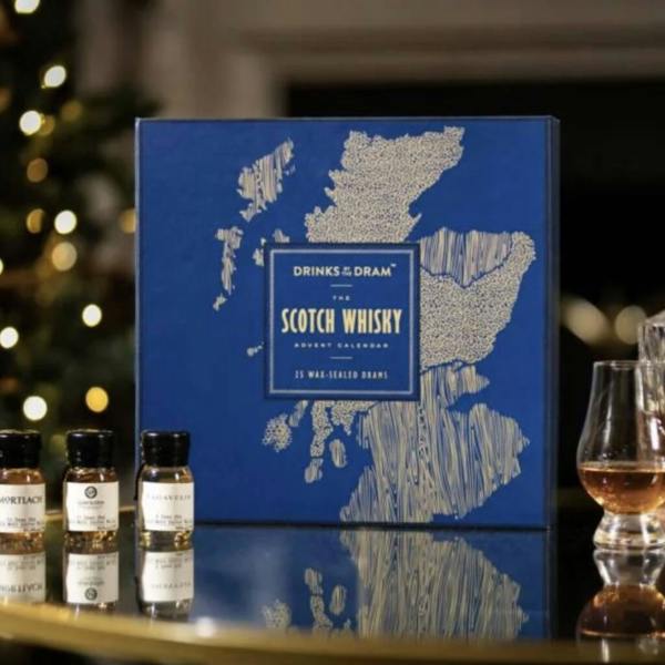 A vibrant, multi-coloured holiday alcohol advent calendar box featuring playful illustrated scenes of a Scottish whisky distillery layout.