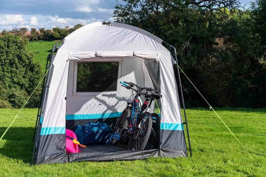 The OLPRO Pod Kitchen/Storage Tent pitched on a campsite with some bikes stored inside.