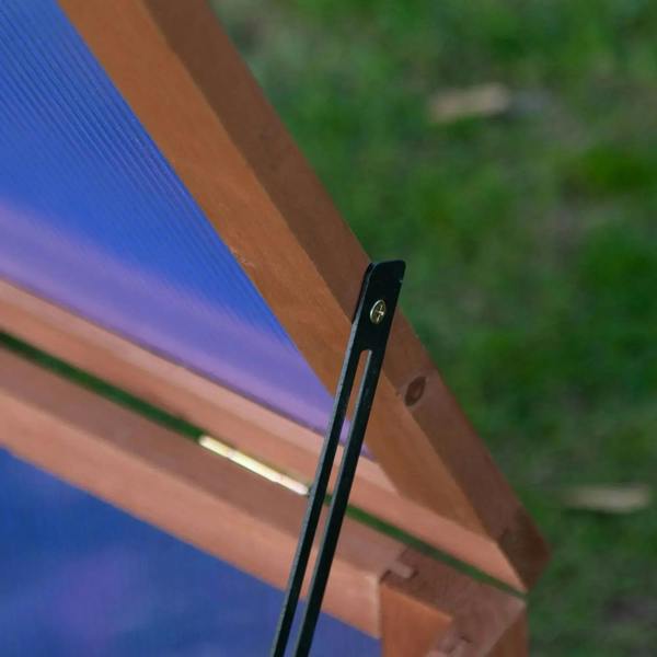 Close-up of hinged support rod holding the open top of a wooden cold frame