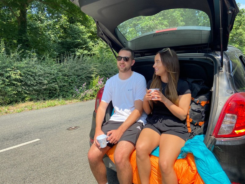 Two adults sitting on a Insulated Outdoor Reversible Blanko in the back of a Car.