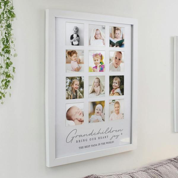 A large white multi photo wall frame showcasing 12 square pictures of babies and children, featuring the custom printed quote Grandchildren bring our heart joy.