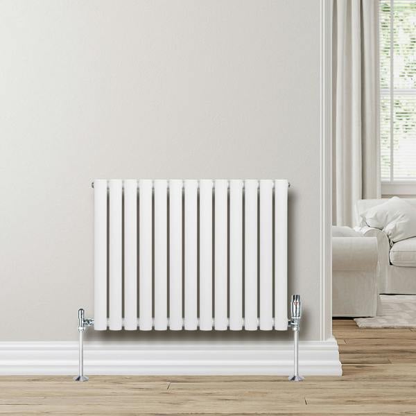 White oval single column radiator, 600 x 780mm, mounted on a wall with chrome valves, complementing a modern living room setting