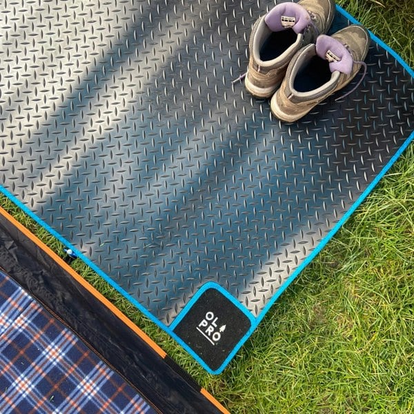 OLPRO Awning Tunnel Mat 1500mm x 800mm Black Rubber with Blue Edge Trim being used within a camper van awning with some walking boots being stored on it.