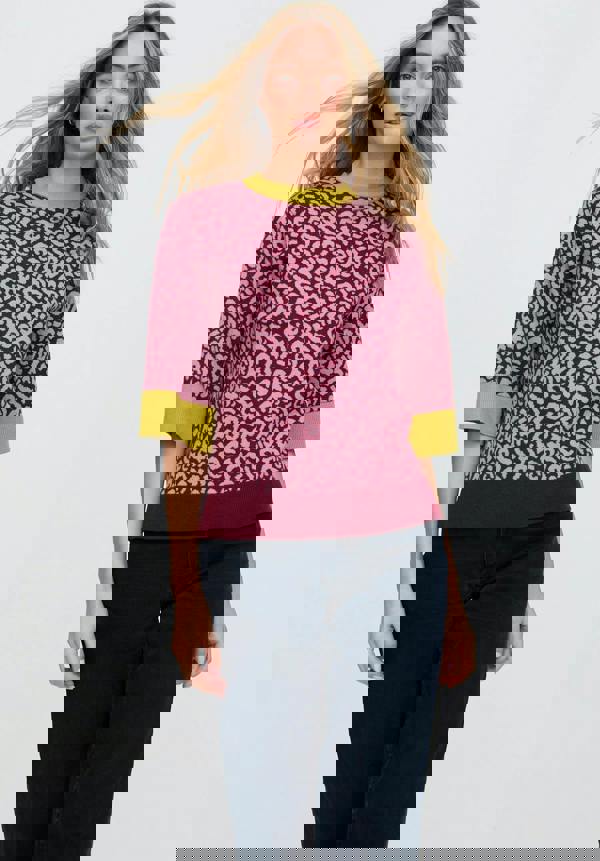 Woman wearing a pink leopard print sweater with green accents on a white background