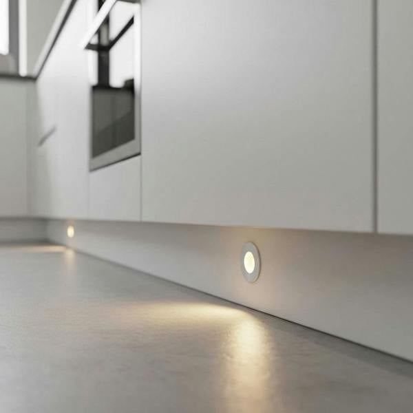 Silver LED kickboard lights installed into a white kitchen plinth. 