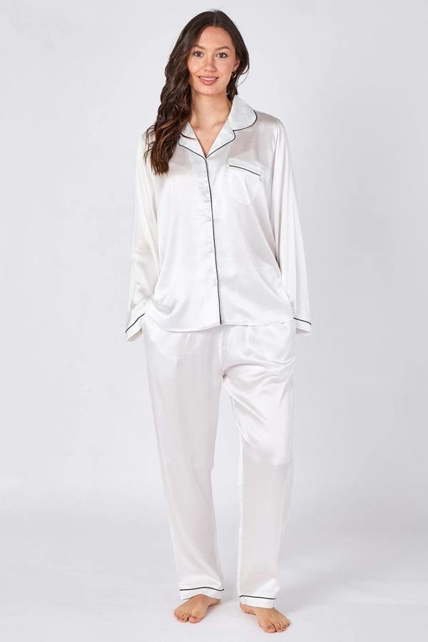 Woman wearing white satin pajamas on a plain background