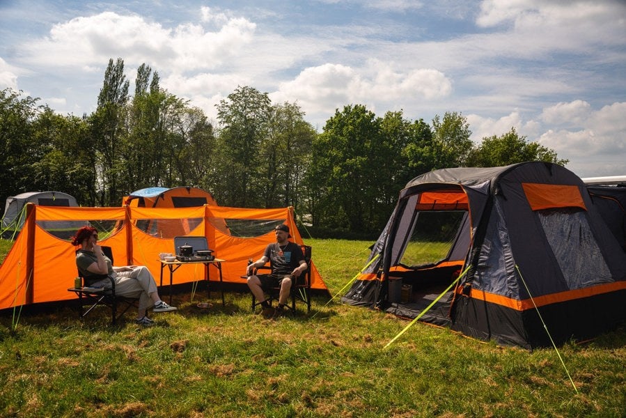 Cubo Breeze® v2 Campervan Awning by OLPRO next to an inflatable windbreak, a couple sit in front of the windbreak in camping chairs imageset:Charcoal