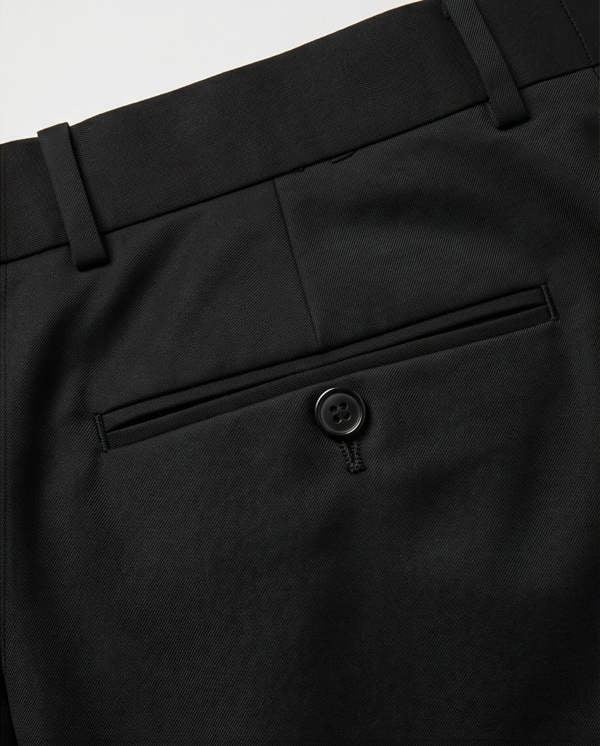 Close-up of black pants with a button on a light gray background