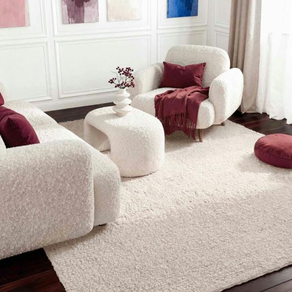 Living room with white furniture, red cushions, and a vase with flowers.