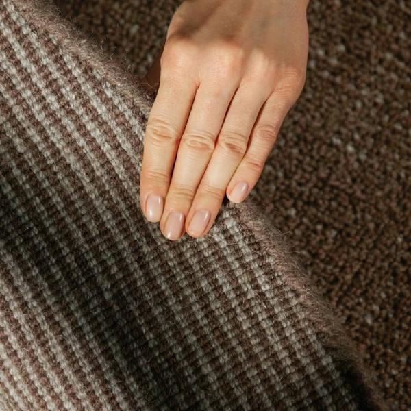 Hand resting on a textured brown fabric surface