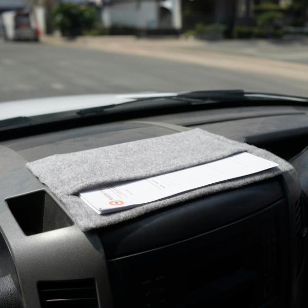 Silver grey storage pouch made of soft felt, neatly placed on a vehicle's dashboard, holding documents securely in place