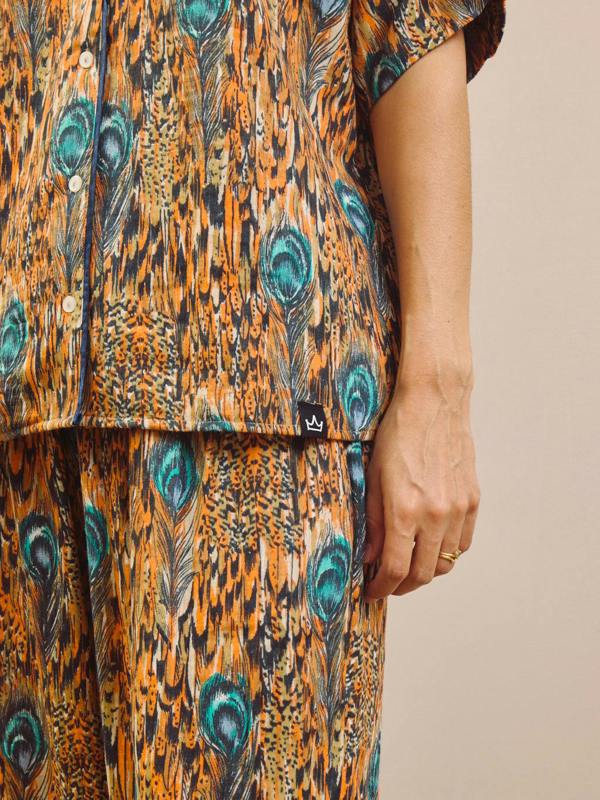 Person wearing a peacock feather pattern pyjama set on a beige background