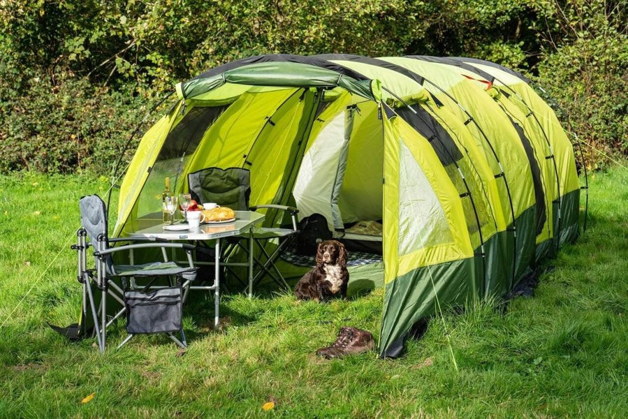 Image of the Abberley XL Extension with a table and two chairs setup for lunch with a dog sat inside and pair of walking boots in the entrance to the Tunnel Tent extension.