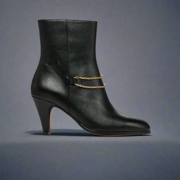 Maya Black ankle boot for bunions with a gold chain on a light gray background