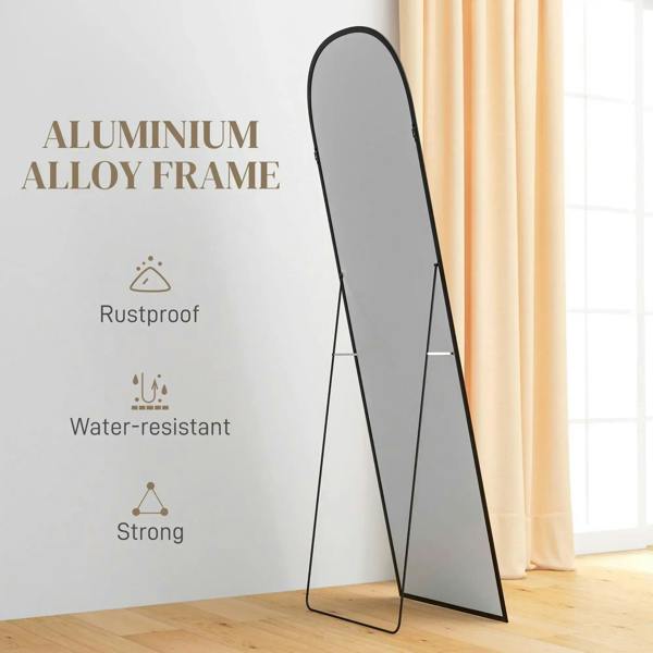 Black standing mirror shown in profile with arched frame and thin legs