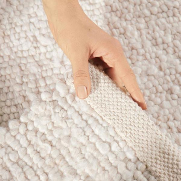 Hand touching a textured beige carpet