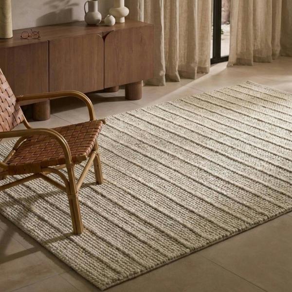 Beige rug on a tiled floor with a wooden chair and sideboard in the background.