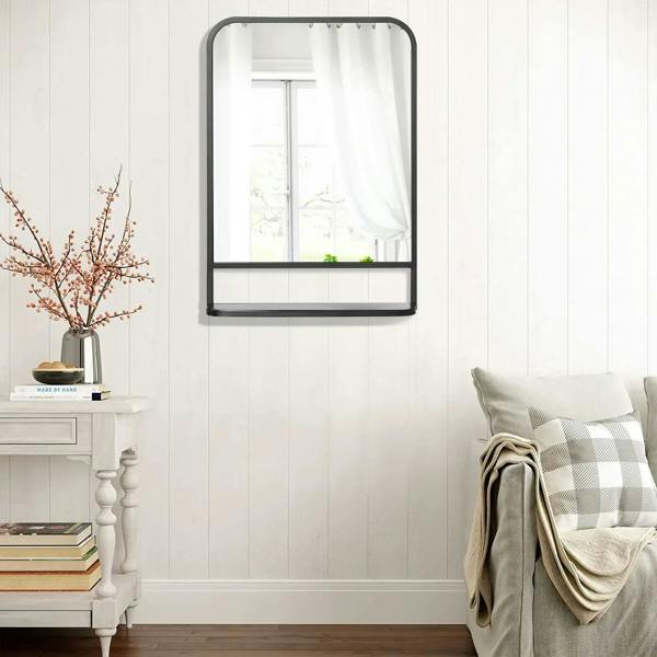 Black wall mirror with storage shelf and rounded rectangular frame.