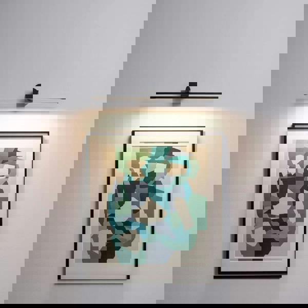 Black over picture light mounted on a white wall over modern artwork 