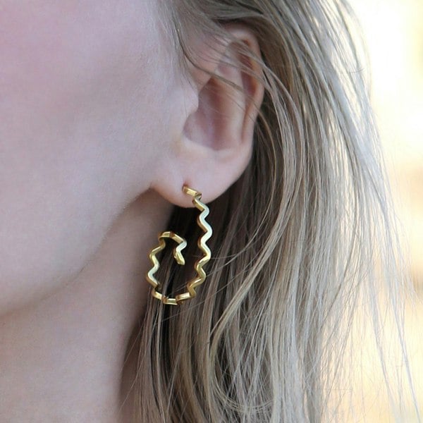 Close up of an ear with zig zag spiral gold vermeil hoop earring.