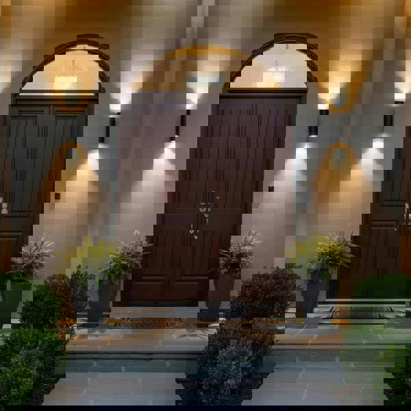 black outside up and down light mounted either side of a brown front door 