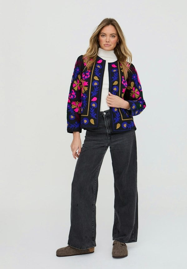 Woman wearing a colorful floral jacket on a white background