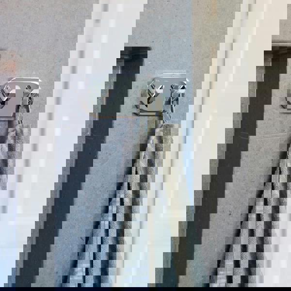 Polished chrome double towel hook on bathroom wall