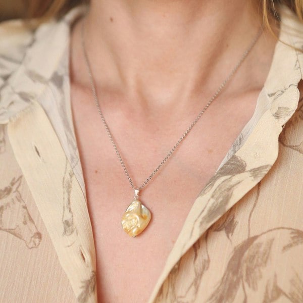 Close-up of natural shell pendant charm by LENAE London, worn by a model.