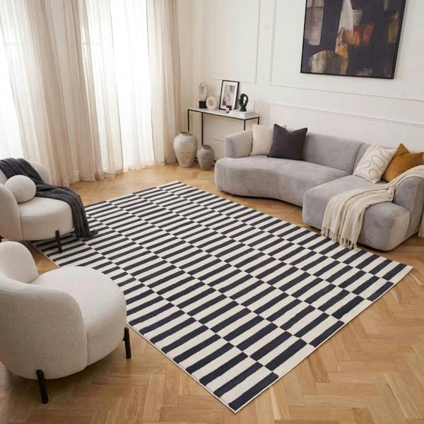 Living room with a striped rug, gray sofa, and white armchair.