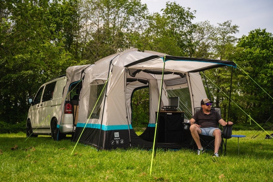 A man sits outside the Snug Poled Tailgate Awning, in an OLPRO directors chair