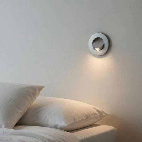 silver recessed wall or bed headboard reading light mounted in a wall next to a bed in a modern bedroom