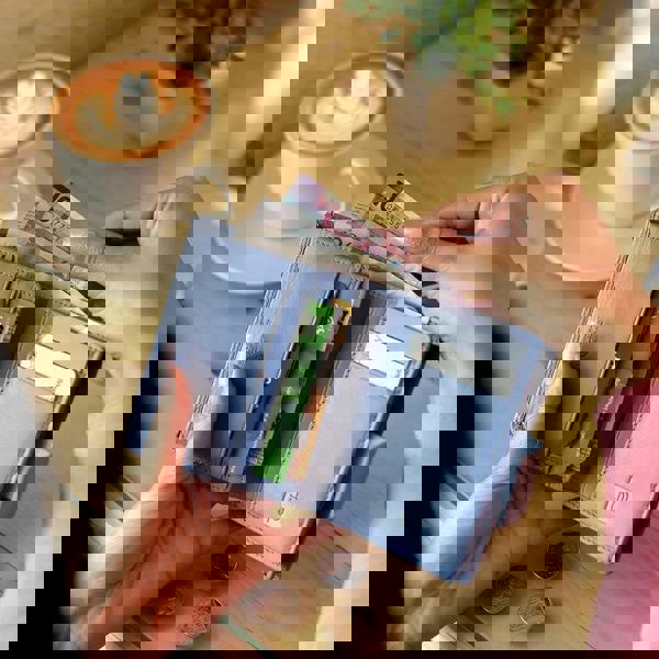 Soft blue leather RFID trifold purse held in hand – lifestyle view