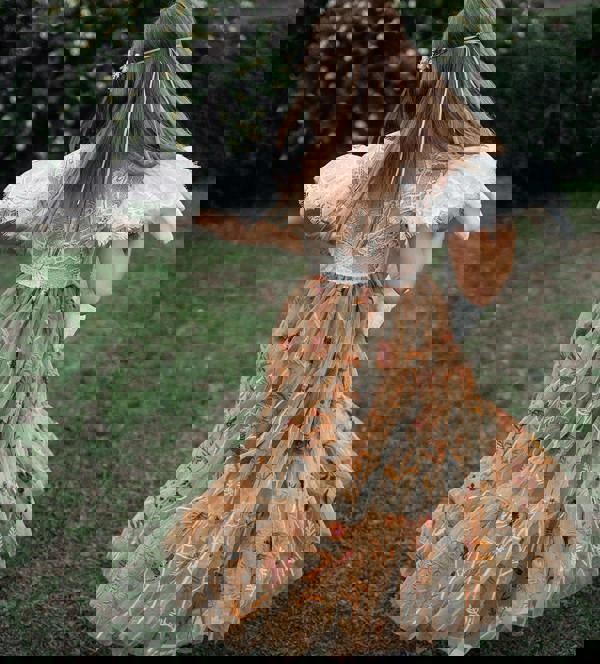 child in a vintage dress with a floral pattern standing outdoors.