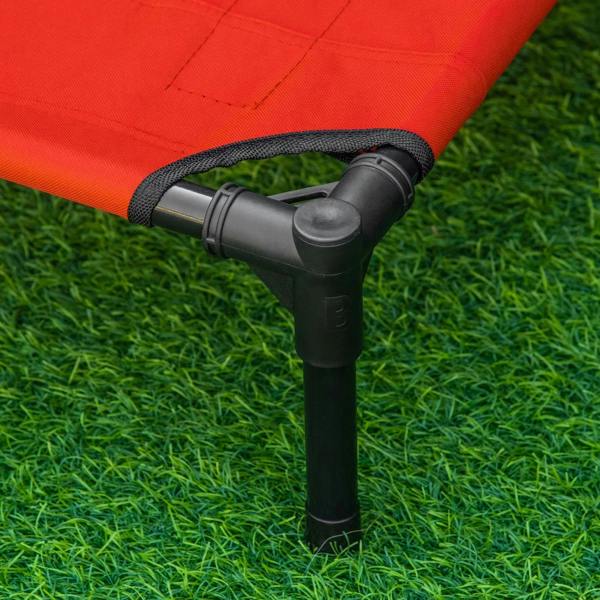 Black metal leg base of a red elevated pet bed with protective pads on grass