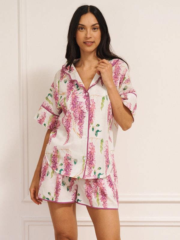 Model wearing white cotton voile oversized shortie pyjamas with pink wisteria print, short-sleeve shirt and elasticated waist shorts with pockets.