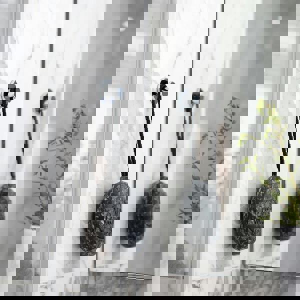 Single polished chrome towel hook on bathroom wall