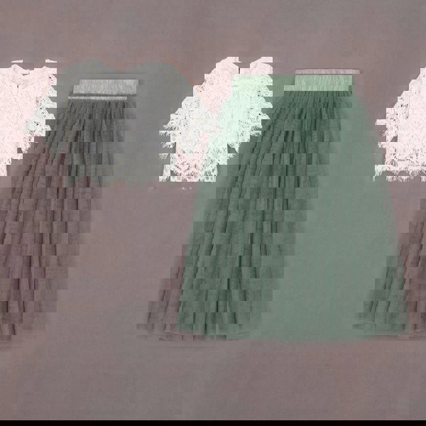 White lace top and green pleated skirt on a brown background