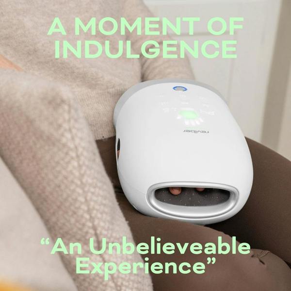 Seated comfortably, someone enjoys a soothing shiatsu massage and gentle air compression with the white Reviber Hand Spa Massager with Heat & Finger Stretch resting on their lap. The text reads: "A MOMENT OF INDULGENCE" and "An Unbelievable Experience.