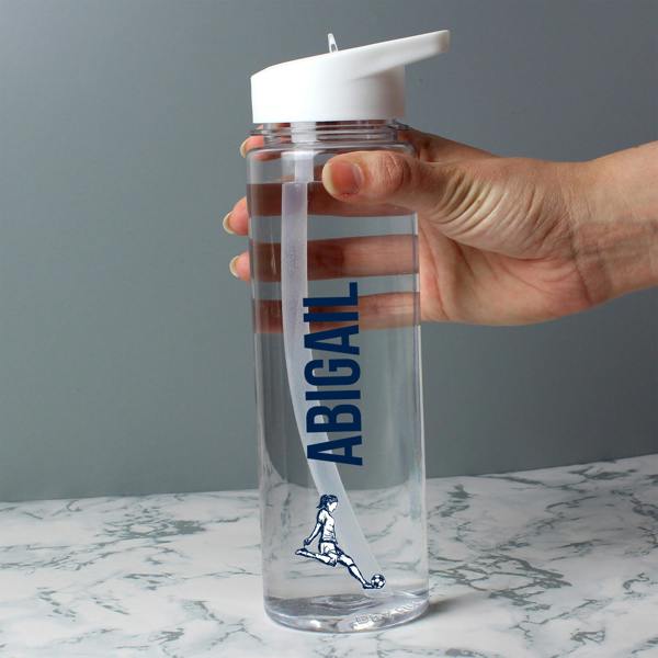 A hand holding a transparent 750ml sports water bottle custom-printed with the name 'Abigail' in navy blue vertical lettering above a female football player graphic.
