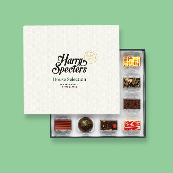 A box of 16 artisan chocolates partially covered by a box lid featuring the name Harry Specters