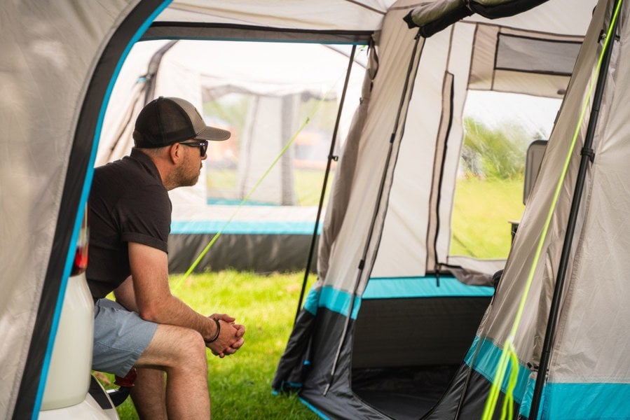 A man sat on the tailgate of A volkswagen T5 inside his snug poled's tunnel