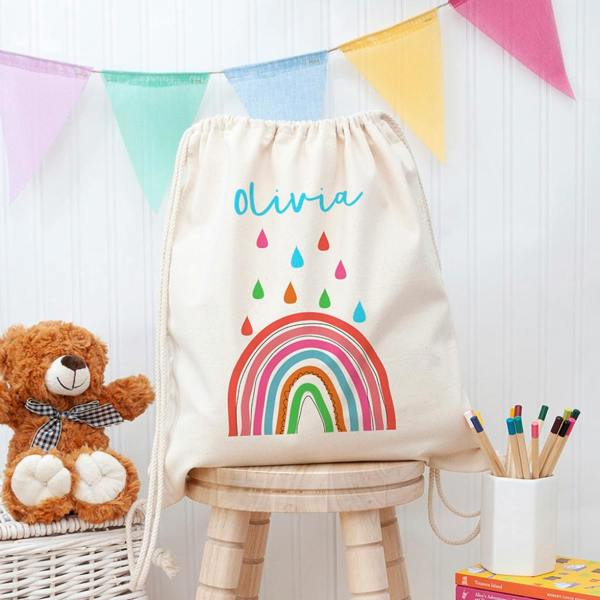 Personalised natural canvas children's PE kit drawstring bag featuring a colourful rainbow print and the name Olivia.