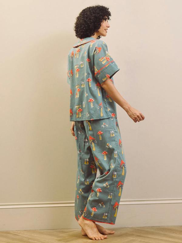 Woman wearing a mushroom patterned oversized pyjama set against a plain background