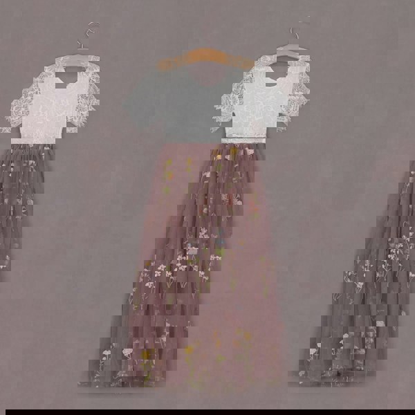 Two-tone dress with lace top and floral skirt on a hanger against a purple background